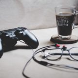 コーヒーとメガネが置かれたテーブルにゲームのコントローラーがある｜Photo by Sabri Tuzcu （instagram.com/saber.shot）