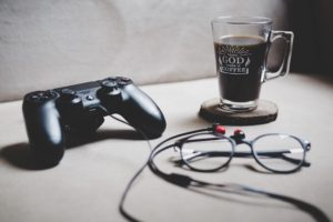 コーヒーとメガネが置かれたテーブルにゲームのコントローラーがある｜Photo by Sabri Tuzcu （instagram.com/saber.shot）